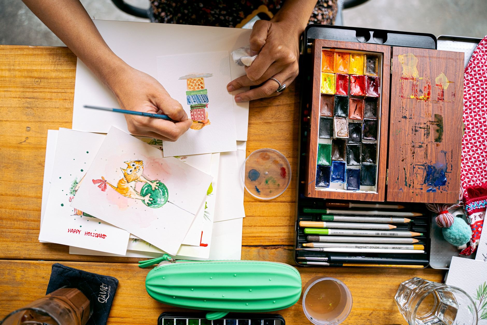 Top view of watercolor painting with vibrant palette and art supplies on a wooden desk